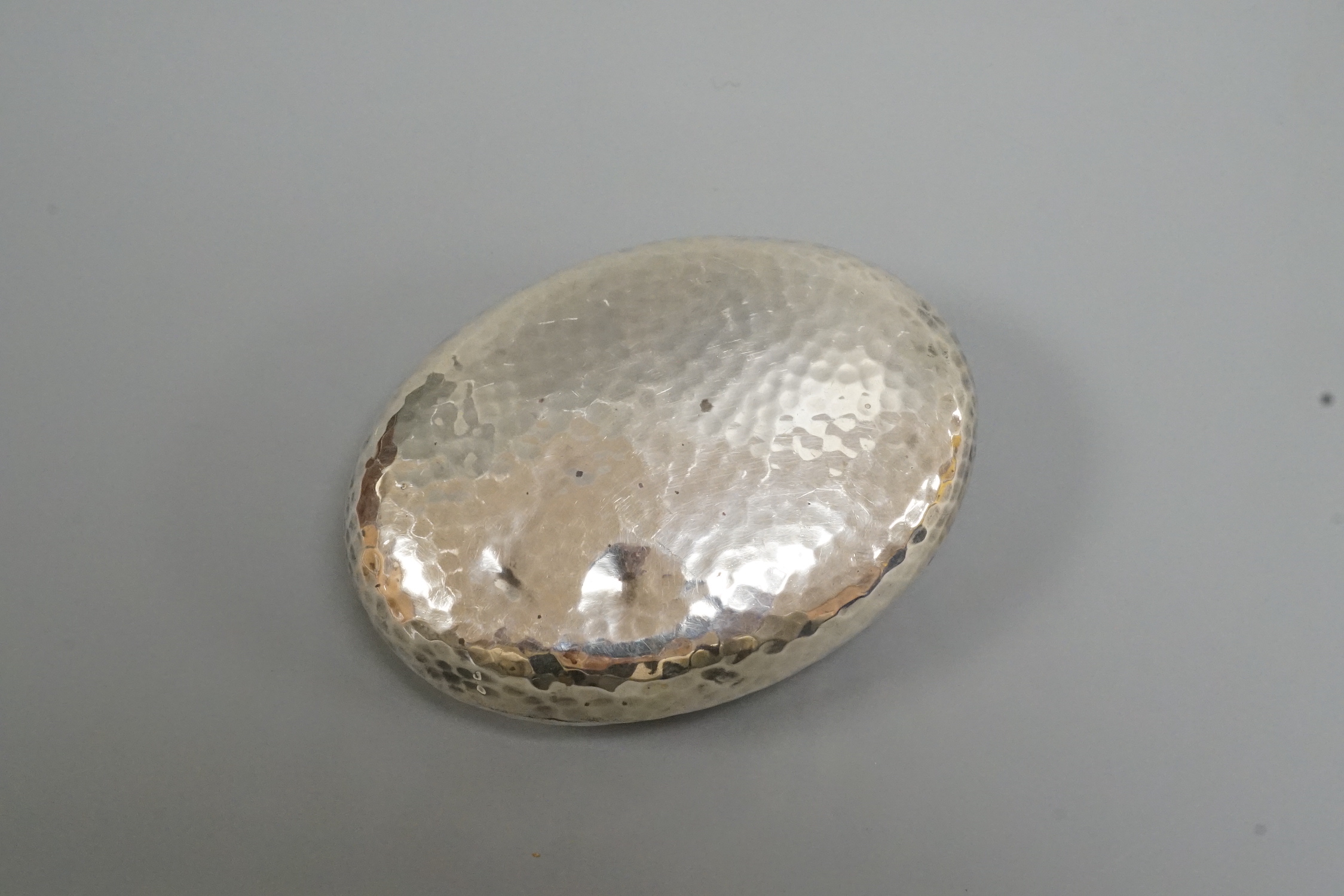 An Edwardian hammered silver oval tobacco box, William M. Hayes, Birmingham, 1908, 86mm.